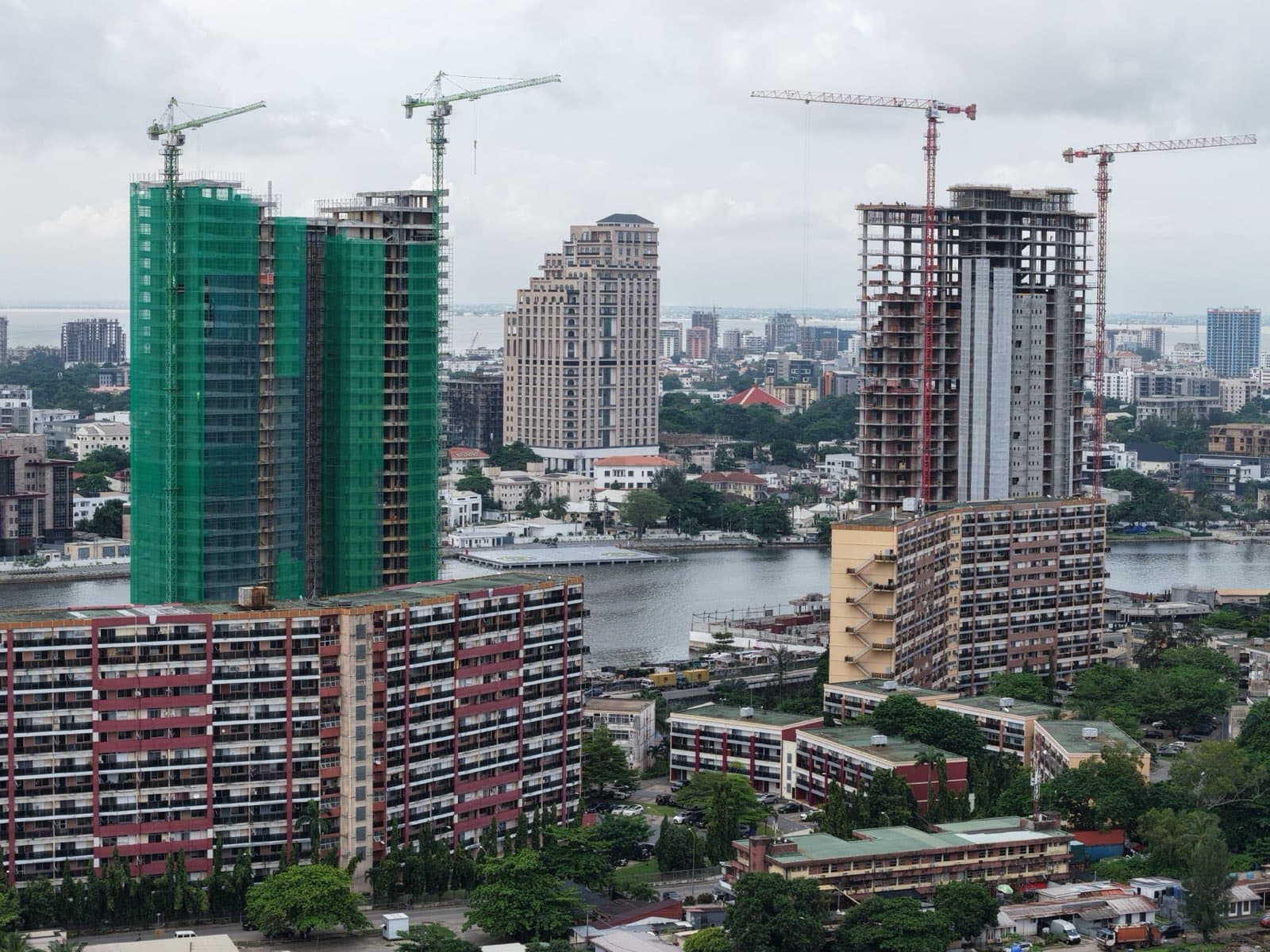 Aerial view of high-rise towers under construction along the Lagos waterfront, with cranes on top