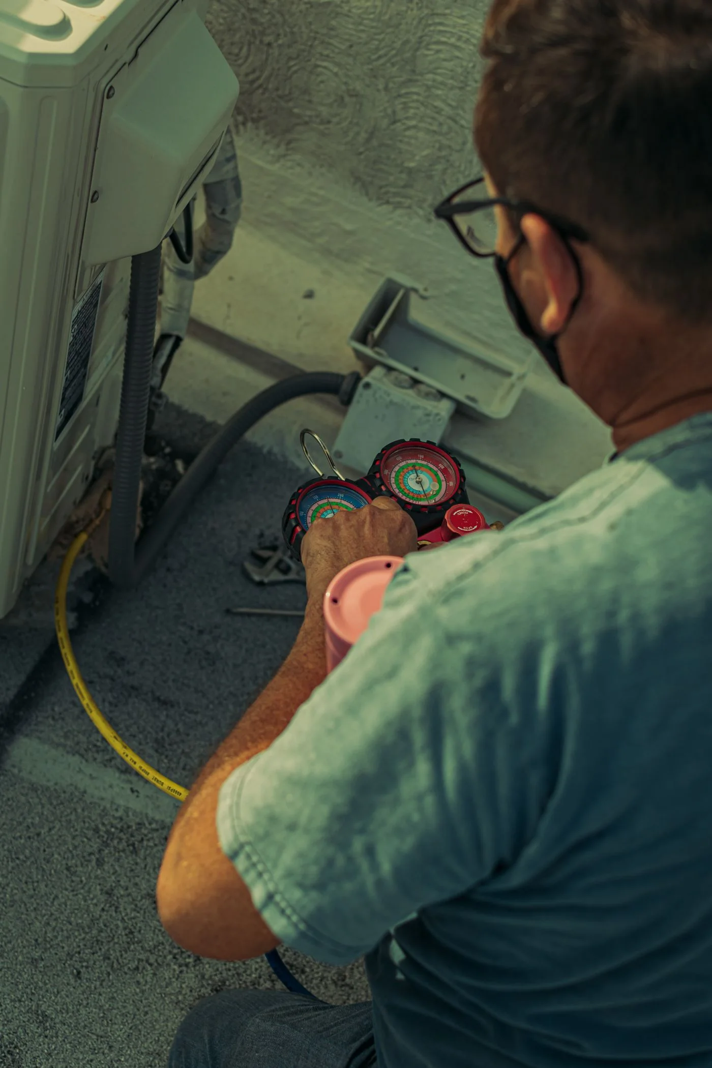 A technician checking an air-conditioning unit with pressure gauges